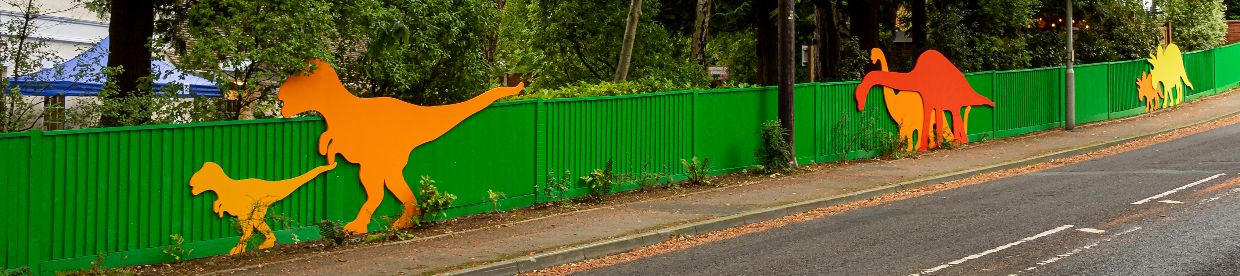 multicoloured fence with wooden dinosaurs