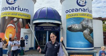Lay holding feeding stick and bag in front of Bournemouth Oceanarium.